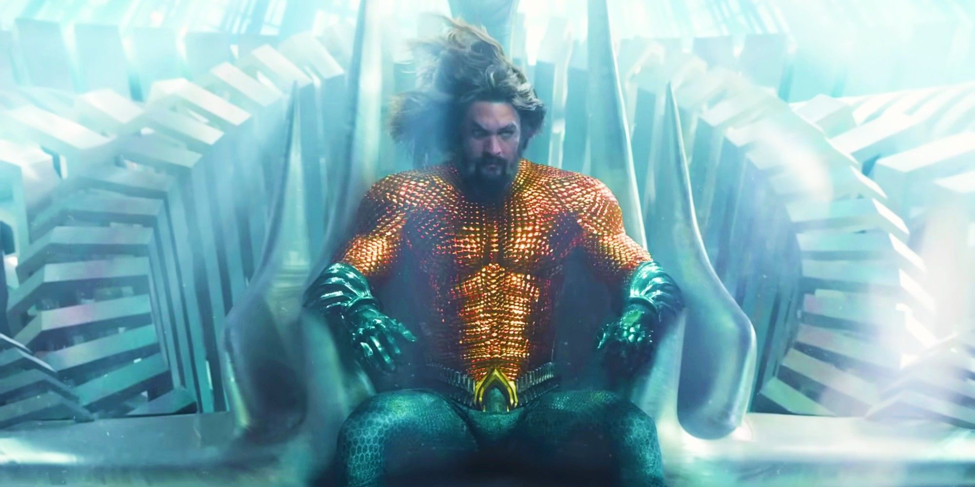 Jason Momoa as Arthur Curry sits on his throne in Atlantis wearing his orange and green suit in Aquaman and the Lost Kingdom