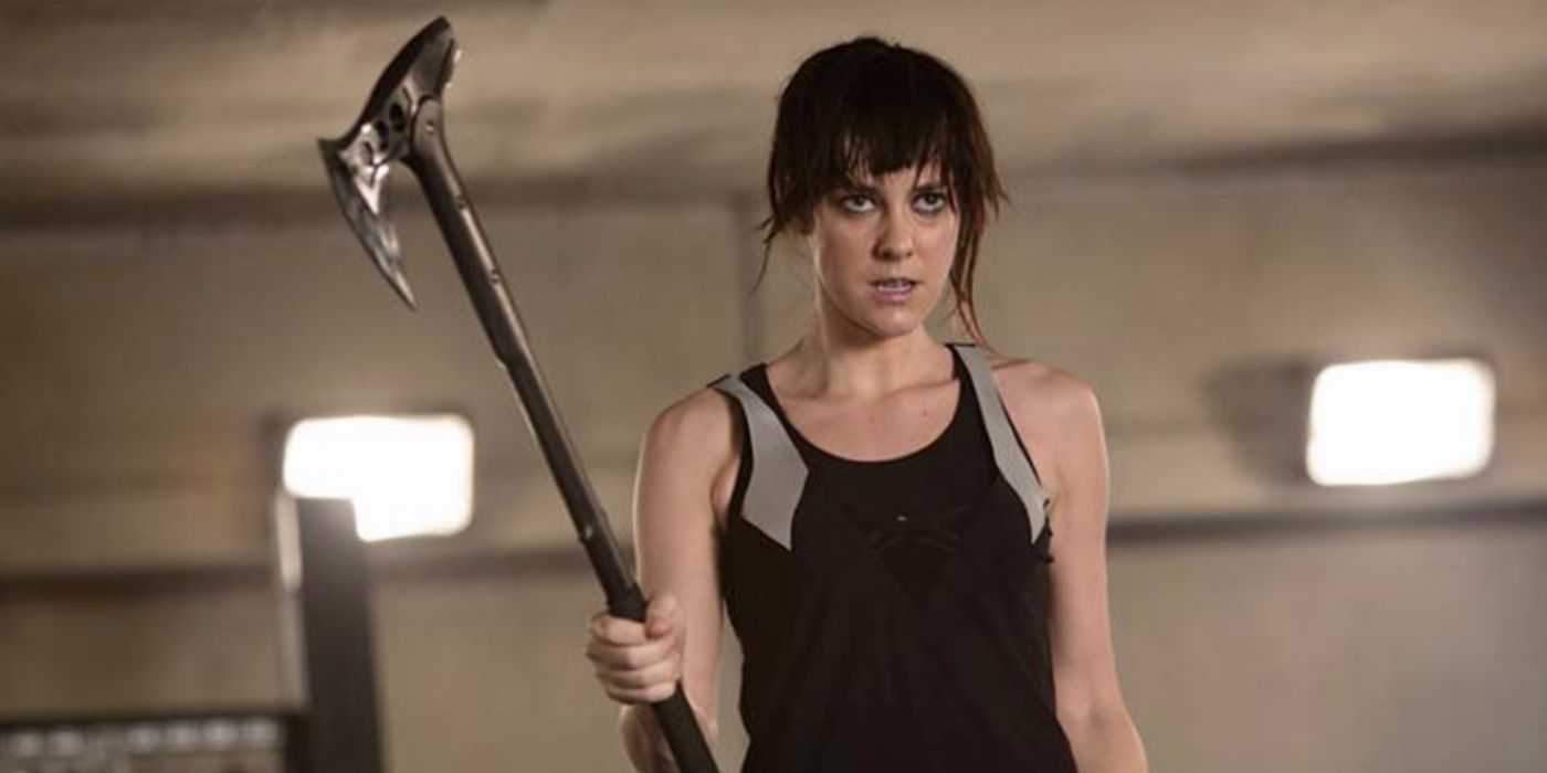 Jena Malone holding an axe in the Hunger Games franchise.