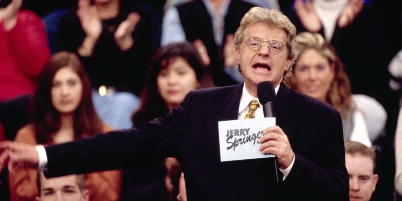 Jerry Springer pointing off camera in front of his audience