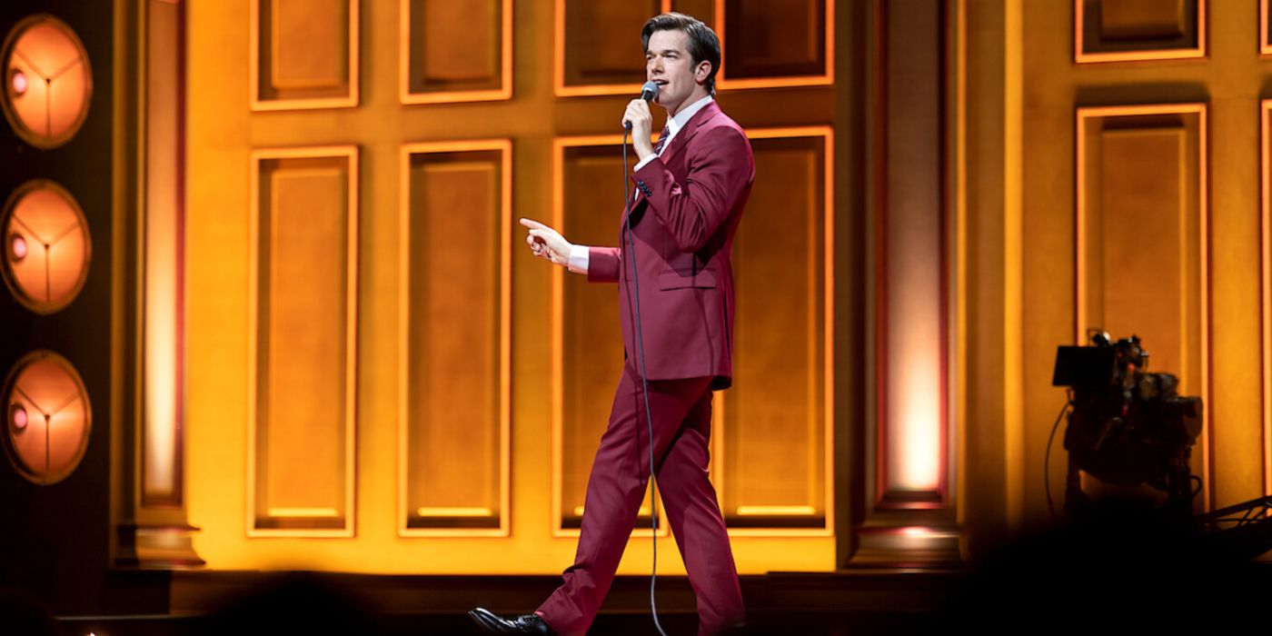 John Mulaney performing stand-up on stage in Baby J