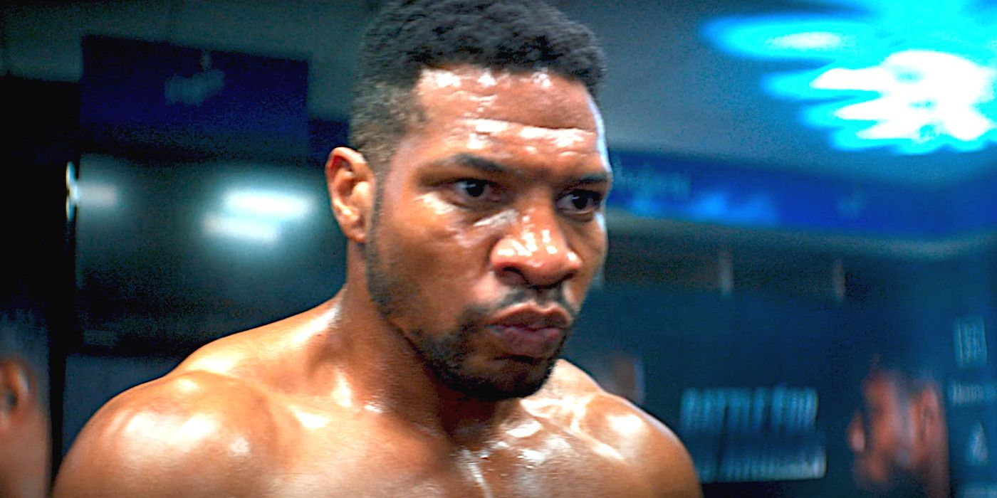 Jonathan Majors as Damian in Creed 3 with his shirt off and muscles bulging, face intently focused ahead of a match