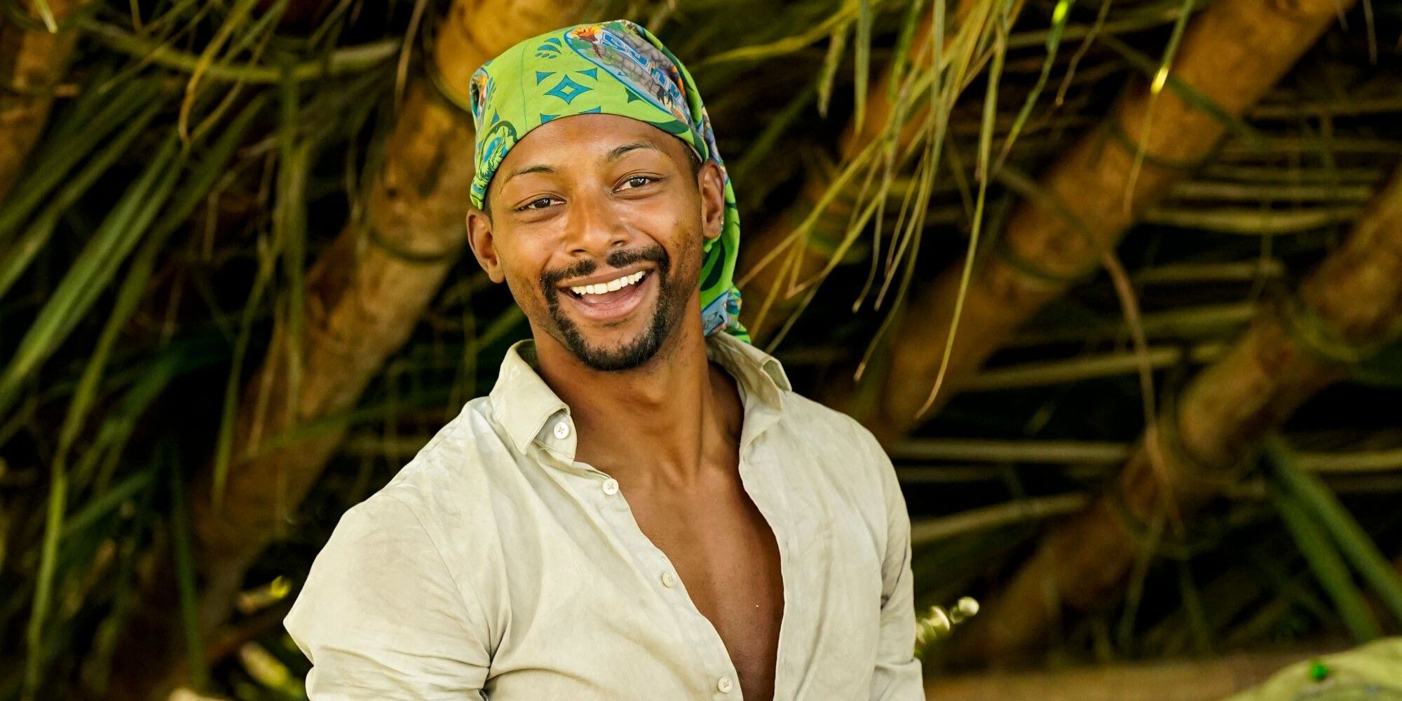 Josh Wilder Survivor 44 smiling on Survivor set wearing green buff as head wrap