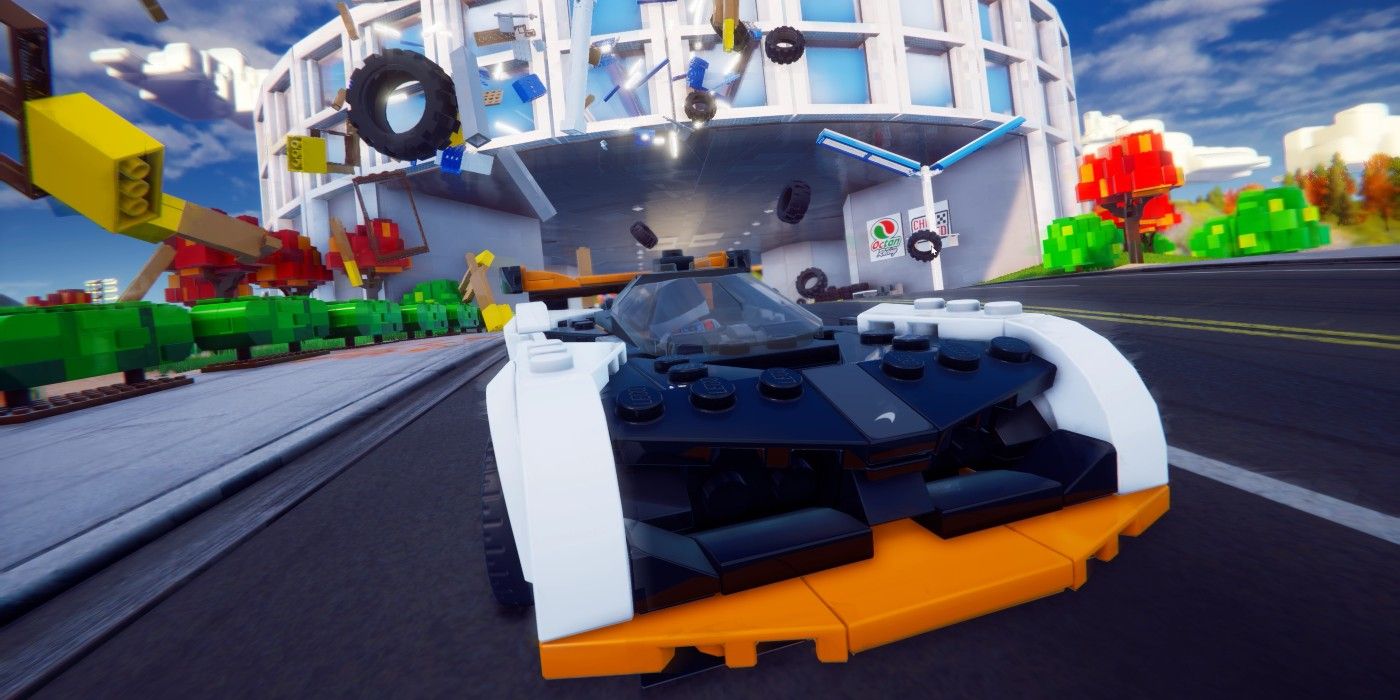LEGO 2K Mengendarai mobil melewati sesuatu yang menyebabkan batu bata LEGO beterbangan di udara.