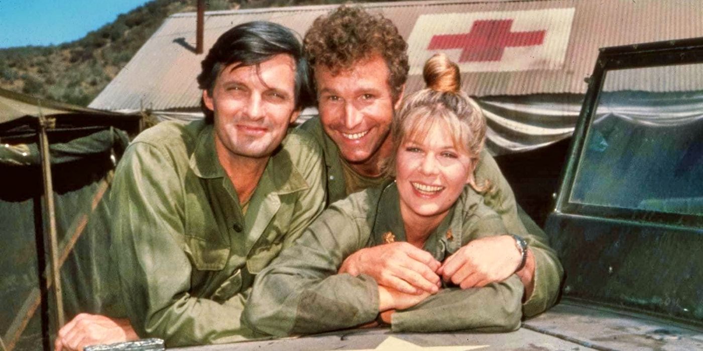 Cast of M*A*S*H leaning on a military truck 