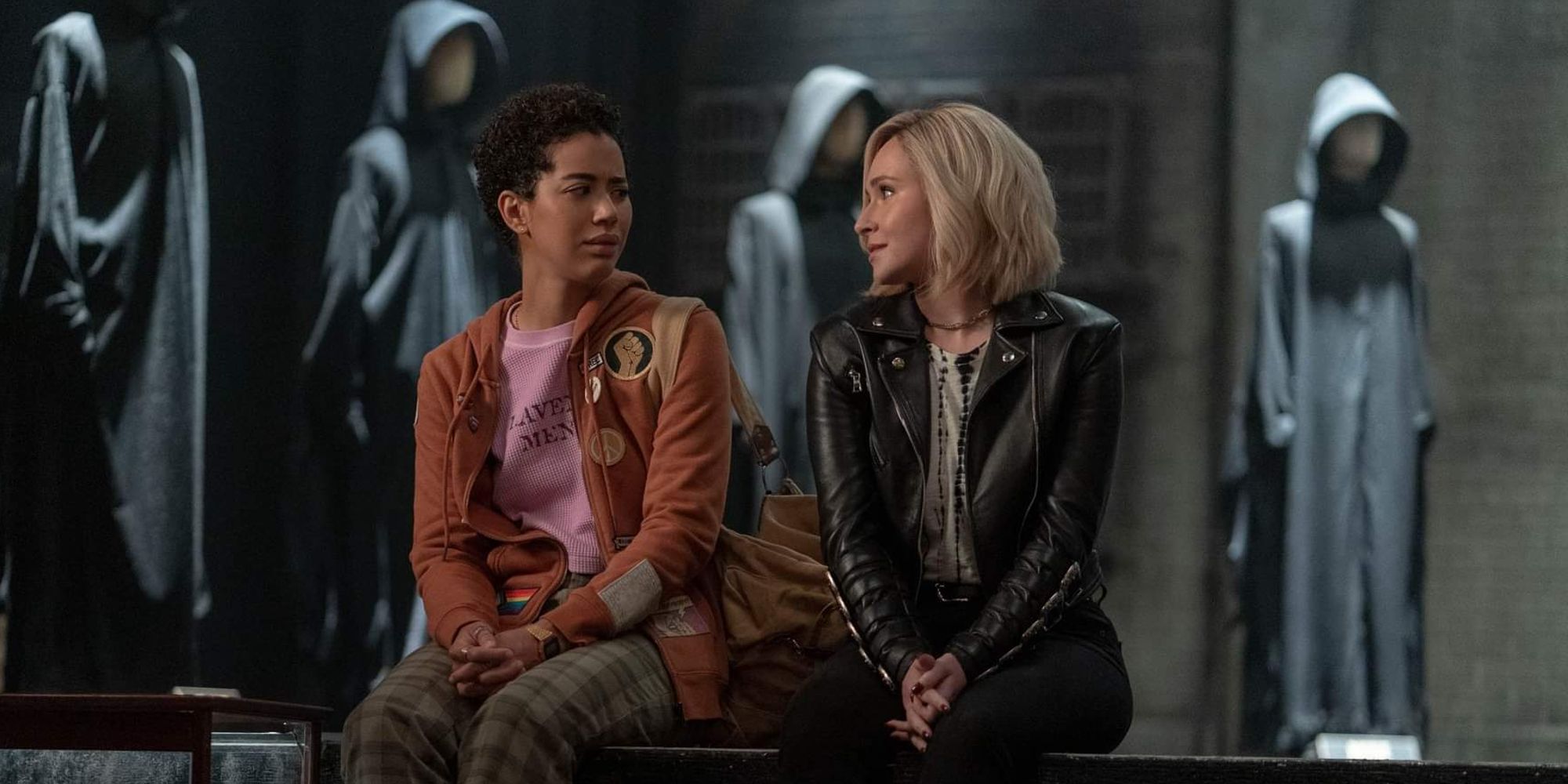 Mindy and Kirby look at each other while sitting on a bench in Scream