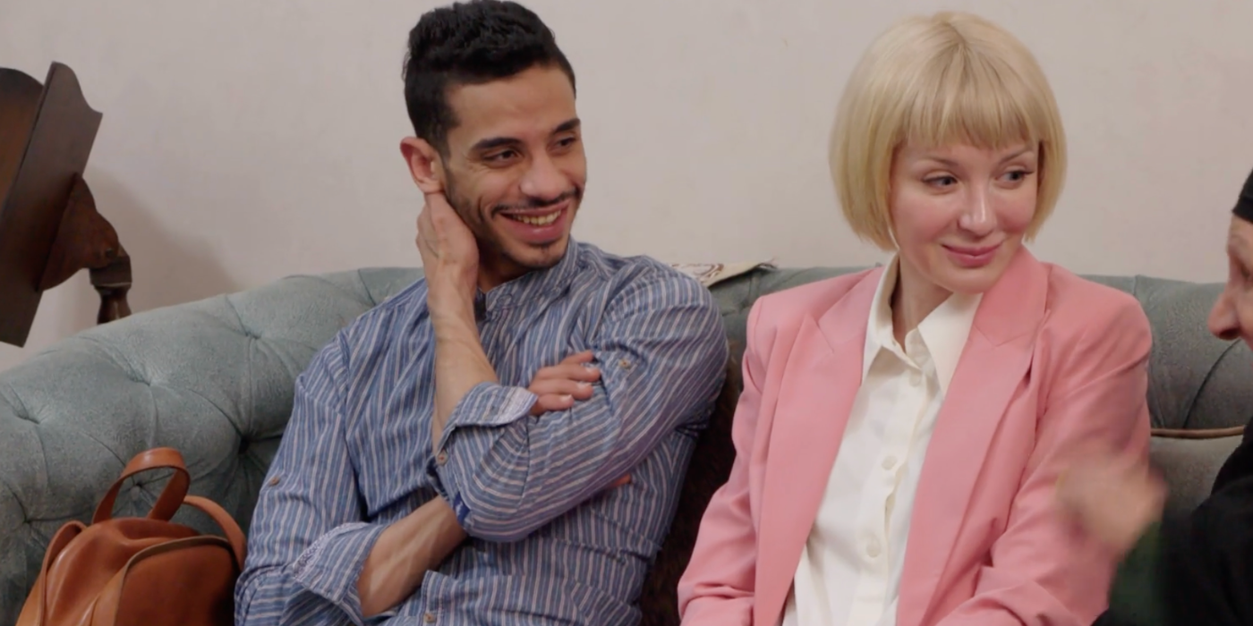 Nicole and Mahmoud In 90 Day Fiancé: The Other Way both dressed in pastels sitting on couch smiling