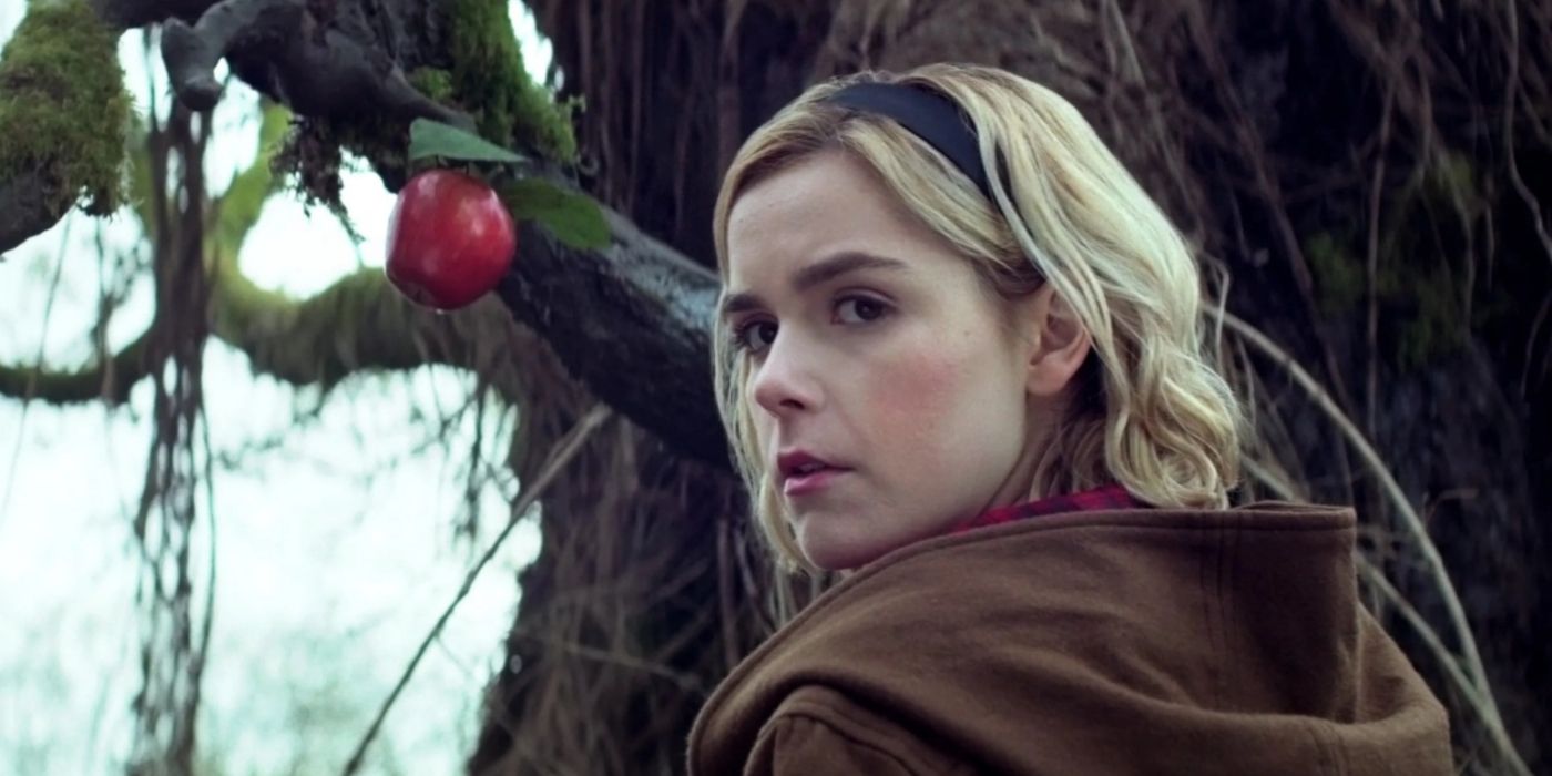 Sabrina stands by an apple tree in Chilling Adventures of Sabrina.