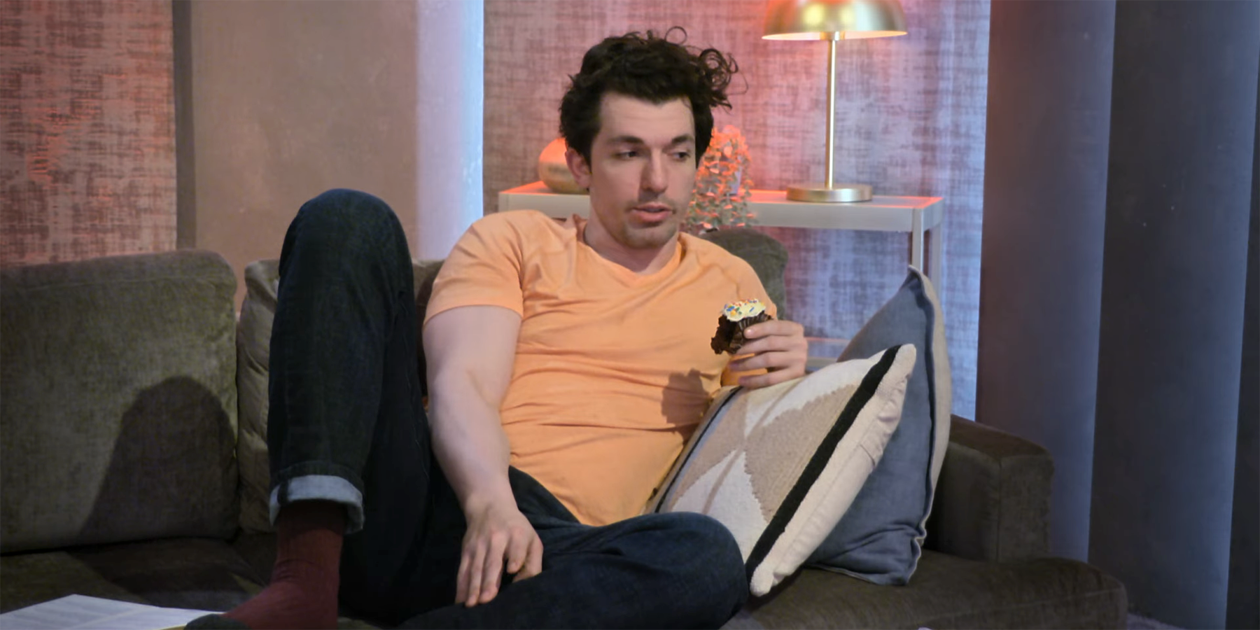 Zack Goytowski from Love Is Blind Season 4 is sitting on the couch eating cupcakes