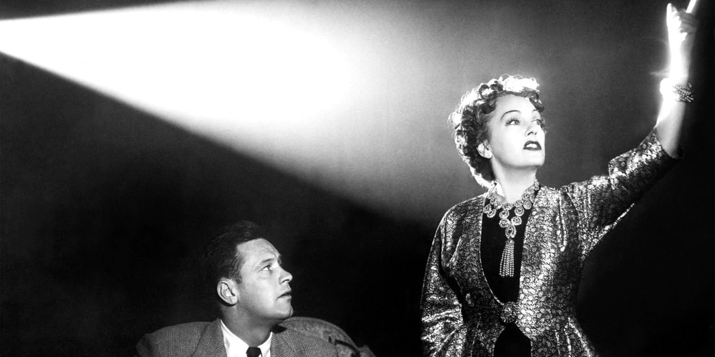Norma stands in the light of a movie projector in Sunset Boulevard 