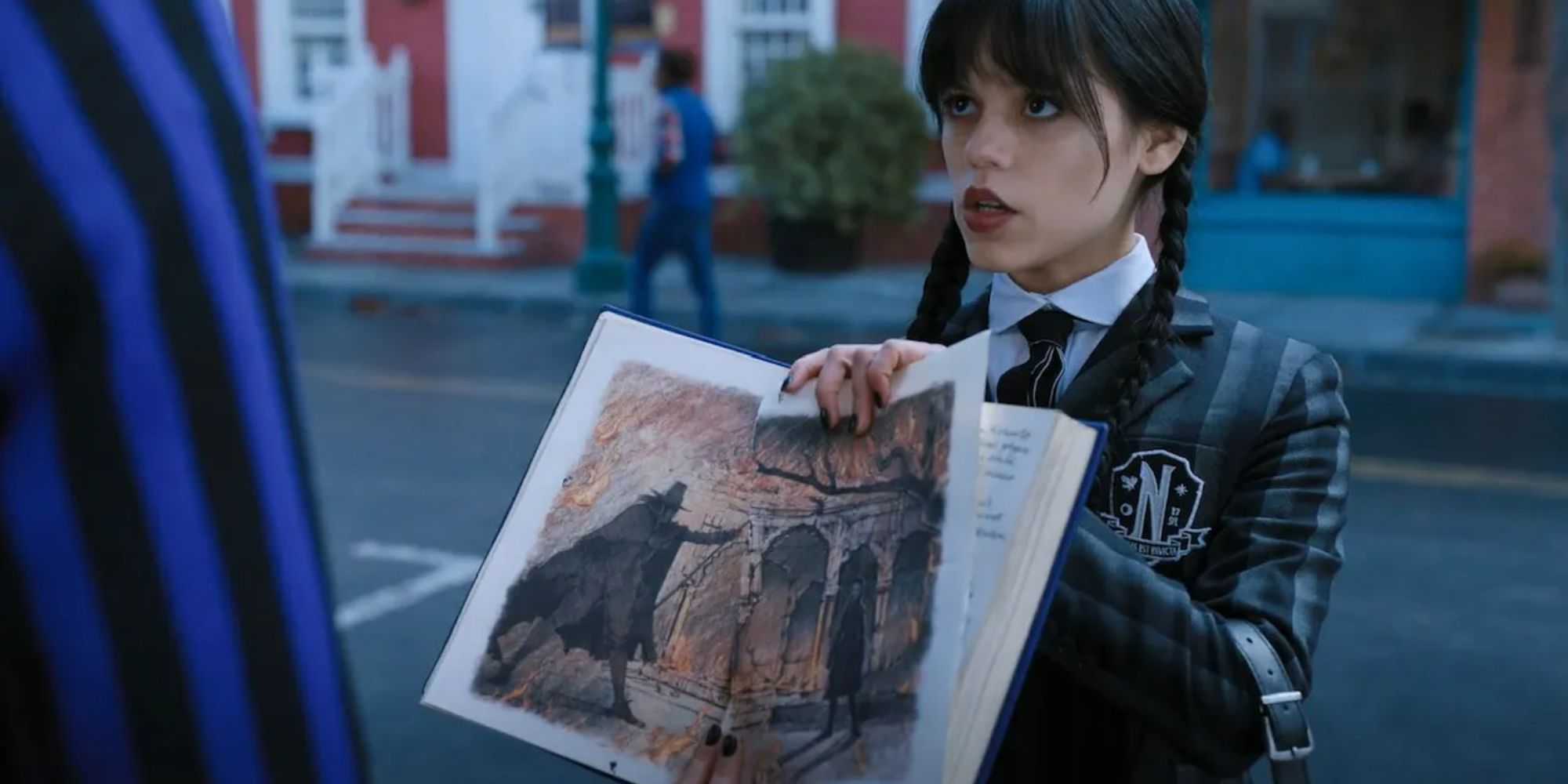 Wednesday (Jenna Ortega) shows an out-of-frame Xavier the drawing of her and Crackstone in Wednesday.