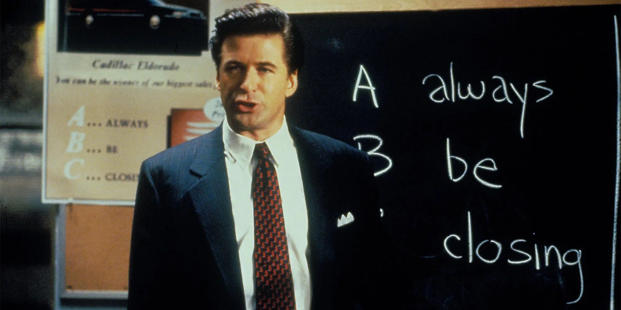 Alec Baldwin giving a presentation with Always Be Closing written on the blackboard behind him in Glengarry Glen Ross