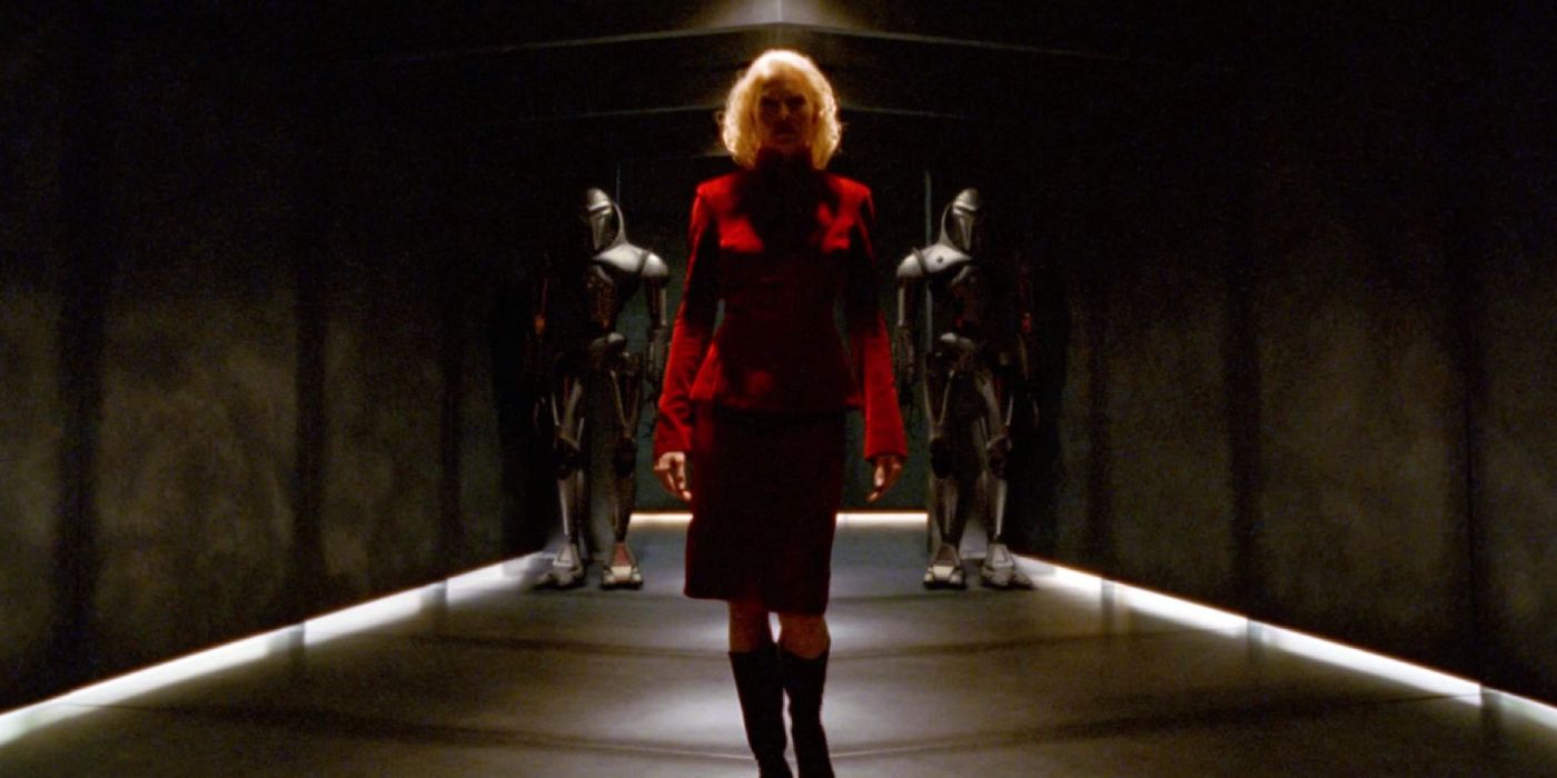 Tricia Helfer walks down a dimly lit hallway as Number Six in Battlestar Galactica.