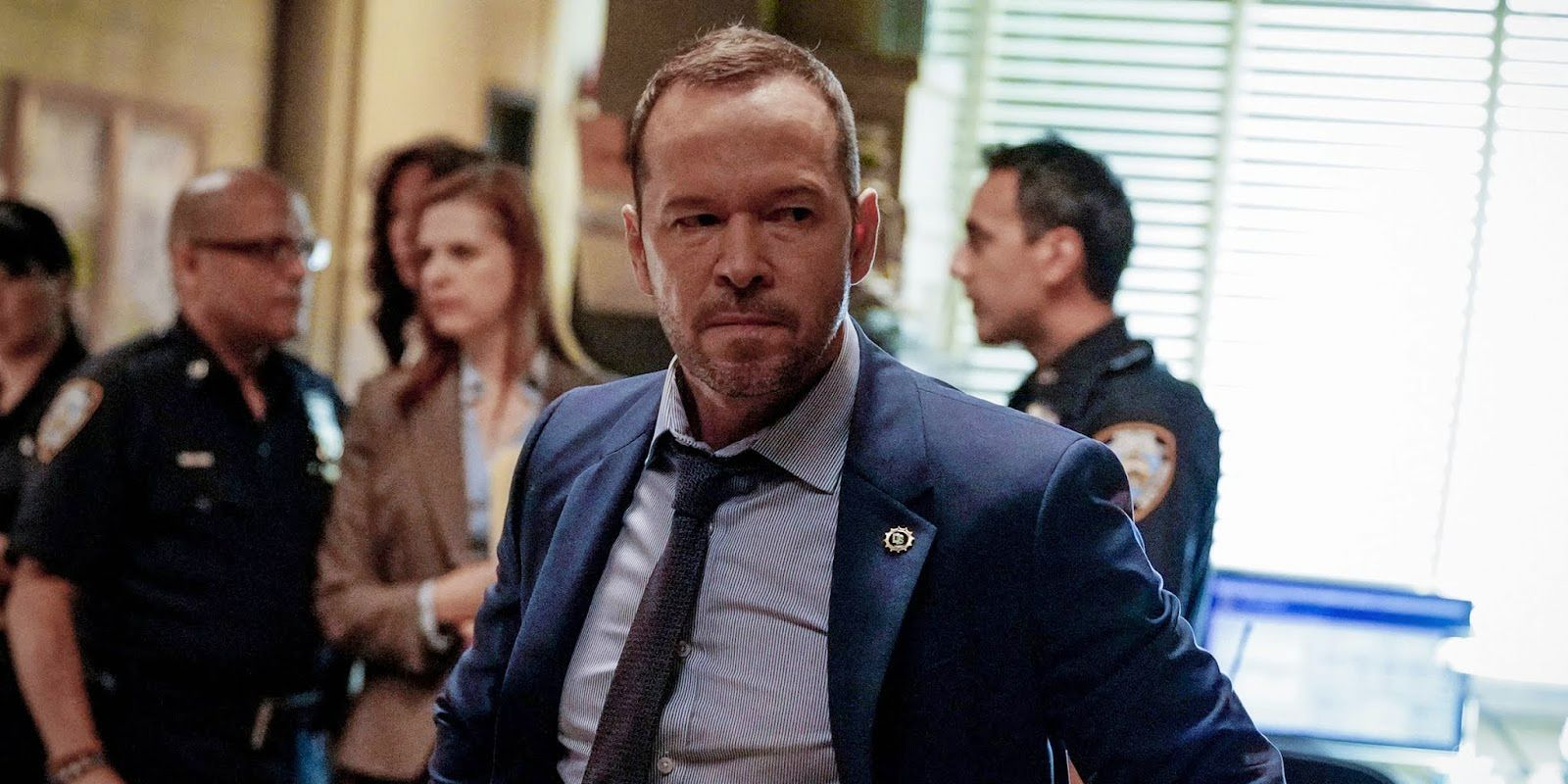 Donnie Wahlberg como Danny parecendo furioso com as pessoas conversando ao fundo em Blue Bloods