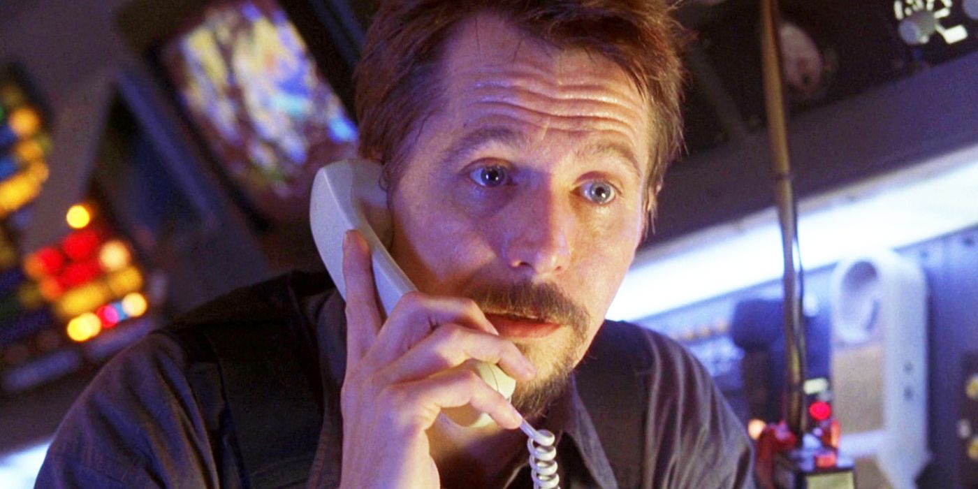 Capture d'écran de Gary Oldman dans Air Force One.  Oldman tient un téléphone près de sa tête dans le cockpit de l'avion.
