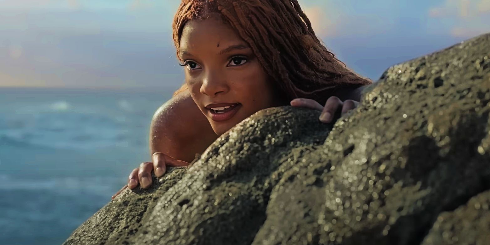 Halle Bailey as Ariel looking out from behind a rock in The Little Mermaid