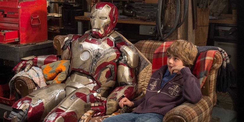 Ty Simpkin as Harley Keener sits on a couch next to damaged Iron Man armor in Iron Man 3