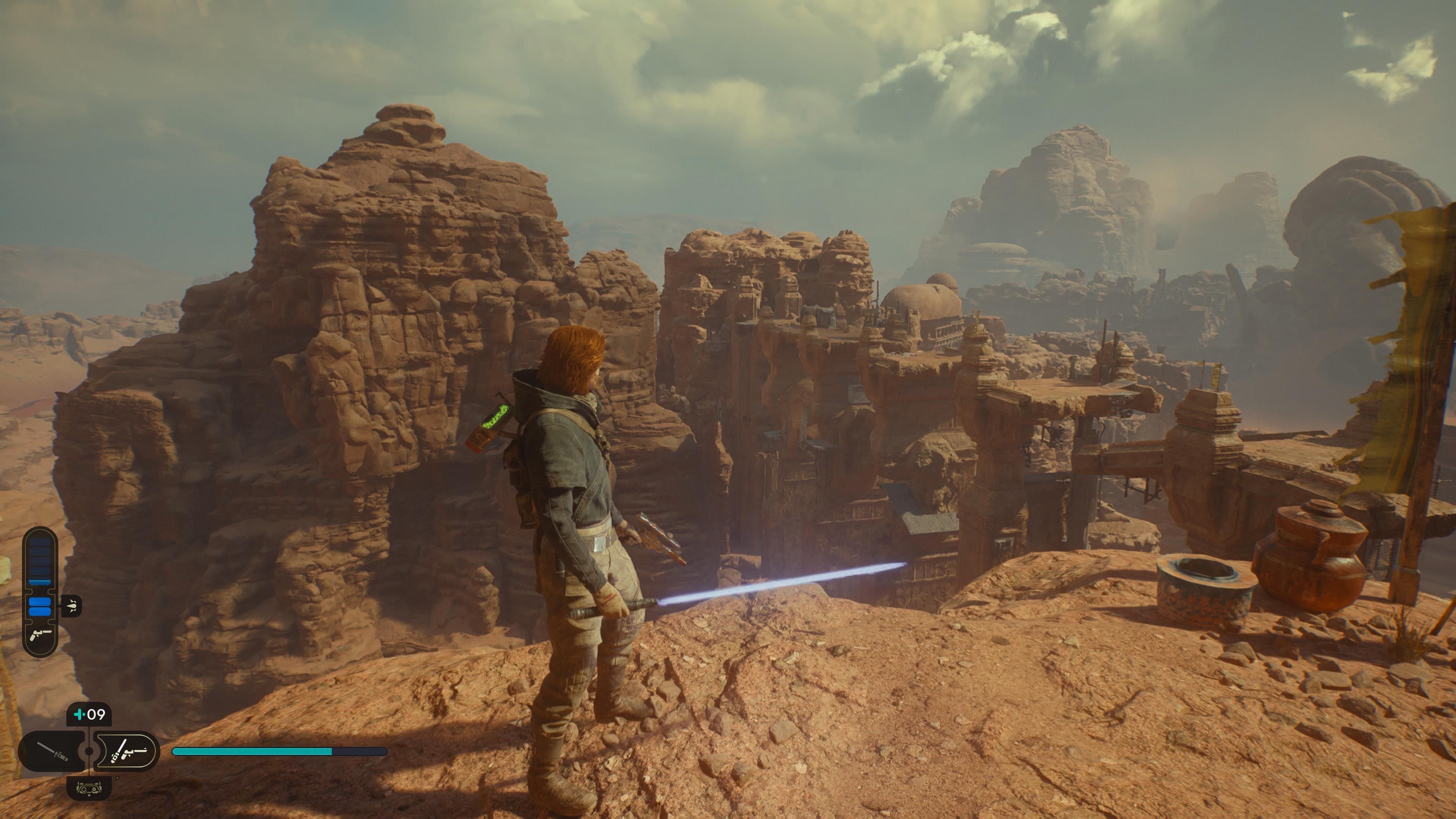 Gameplay screenshot of Cal Kestis standing on a cliff overlooking Jedi ruins on the planet Jedha in Star Wars Jedi: Survivor.