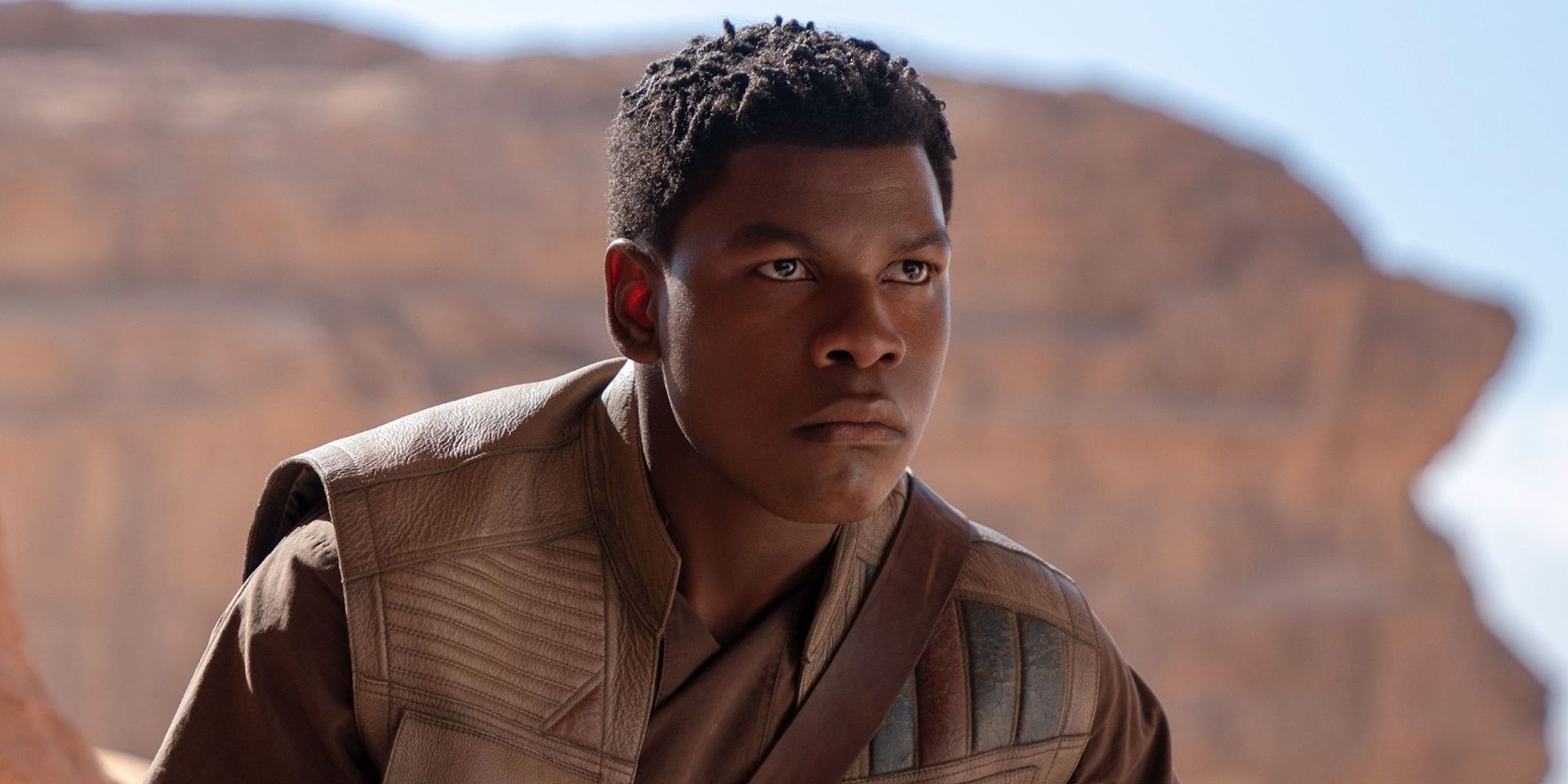 In a dusty landscape Finn stares out into the distance in Star Wars: The Force Awakens