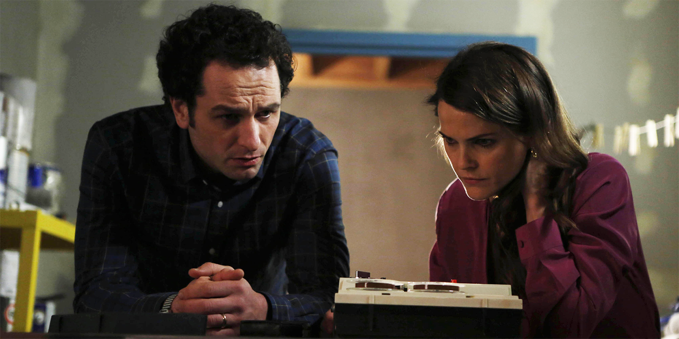 Keri Russell and Matthew Rhys tentatively listening to something in The Americans season 1 