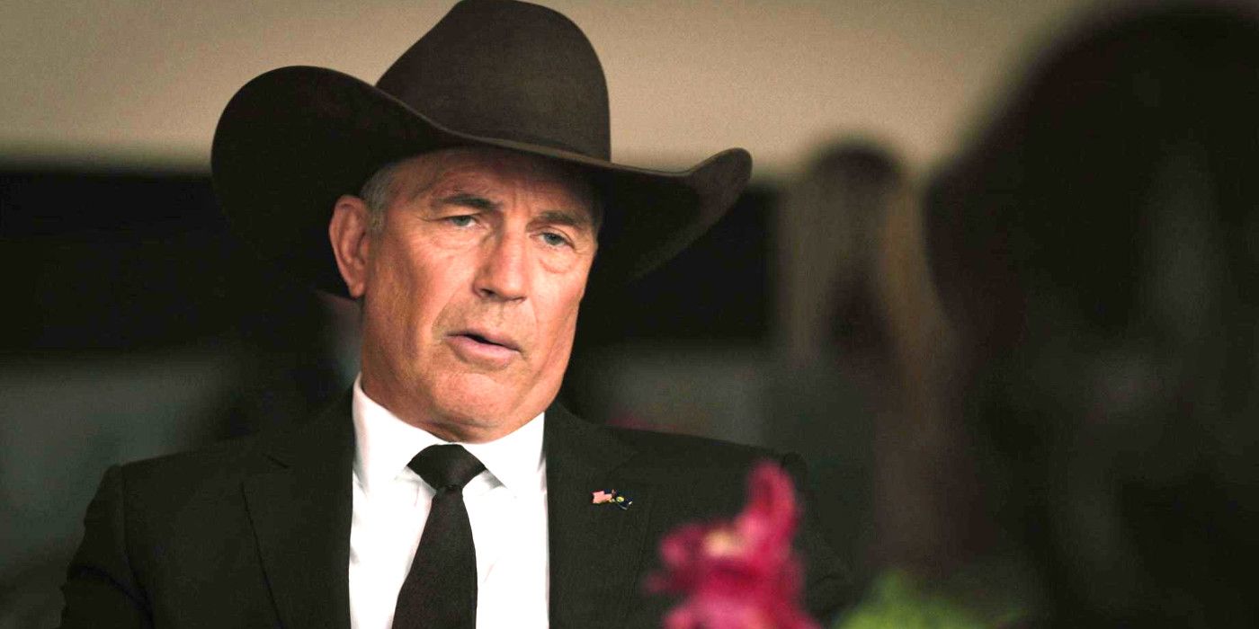 Kevin Costner in Yellowstone in a black cowboy hat at a formal occasional, having a conversation at a table