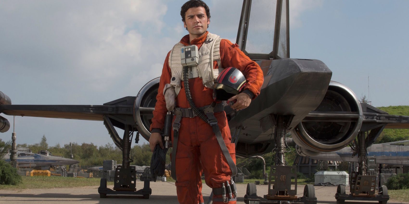 Poe Dameron stands in front of his ship with his helmet over his arm