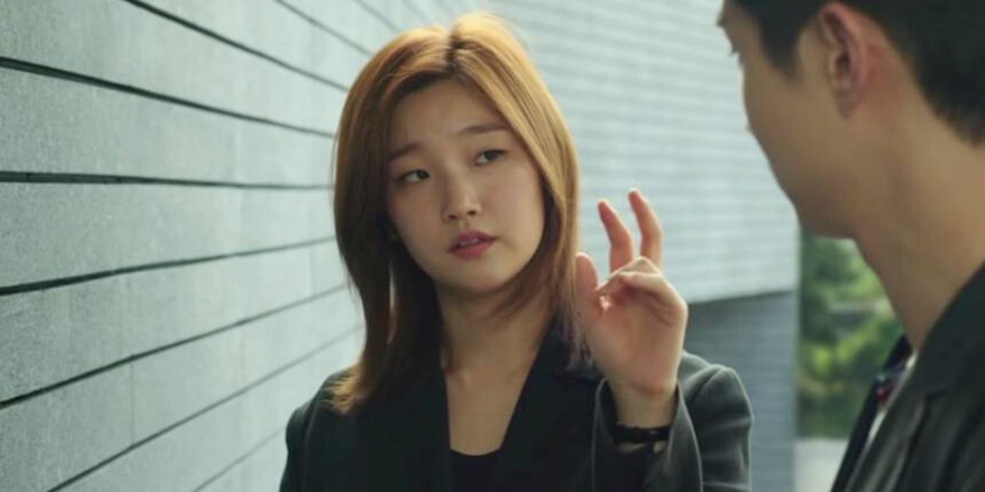 Park So-dam as Kim Ki-jun and Choi Woo-shik as Kim Ki-woo converse behind a house in Parasite.