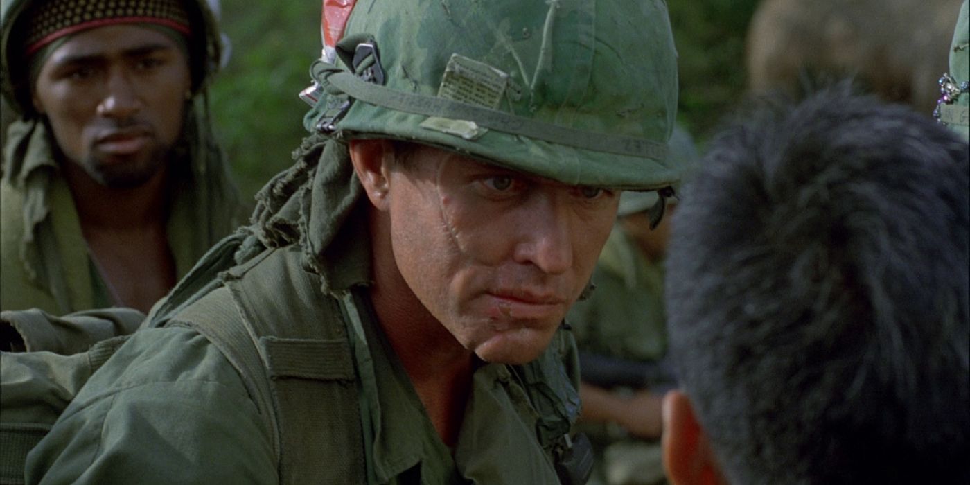Screencap from Platoon 1986. Tom Berenger as Sgt Barnes interrogates a Vietnamese villager while other soldiers look on in the background.