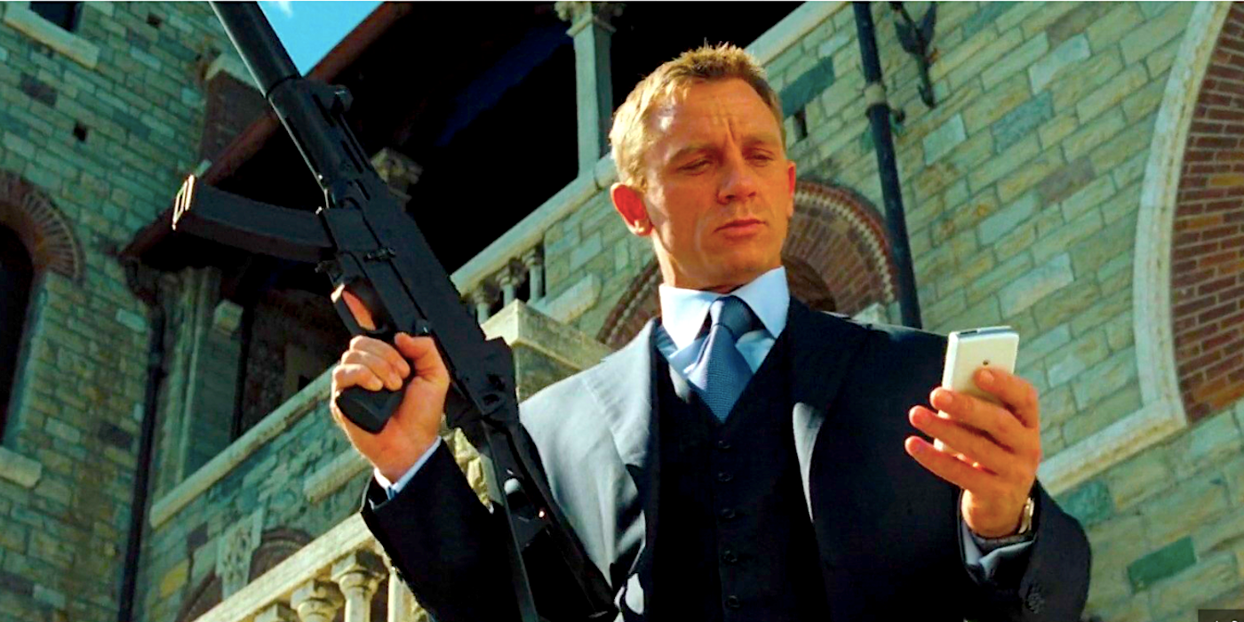 Daniel Craig as James Bond looking at his phone while holding his gun in Casino Royale