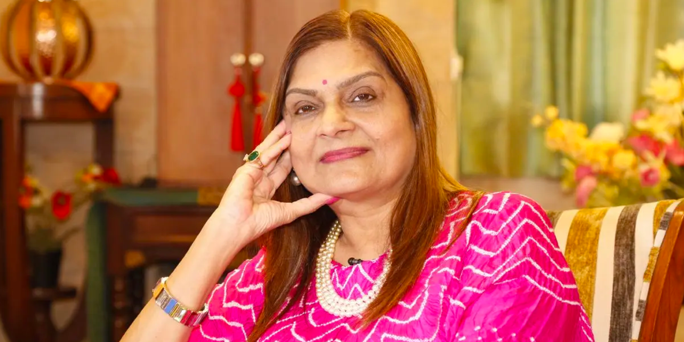 Sima Taparia from Indian Matchmaking in pink dress and jewelry smilng slightly