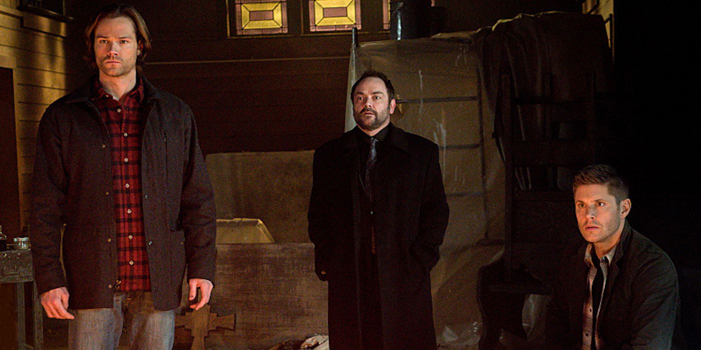 Crowley standing with Sam and Dean Winchester on Supernatural.