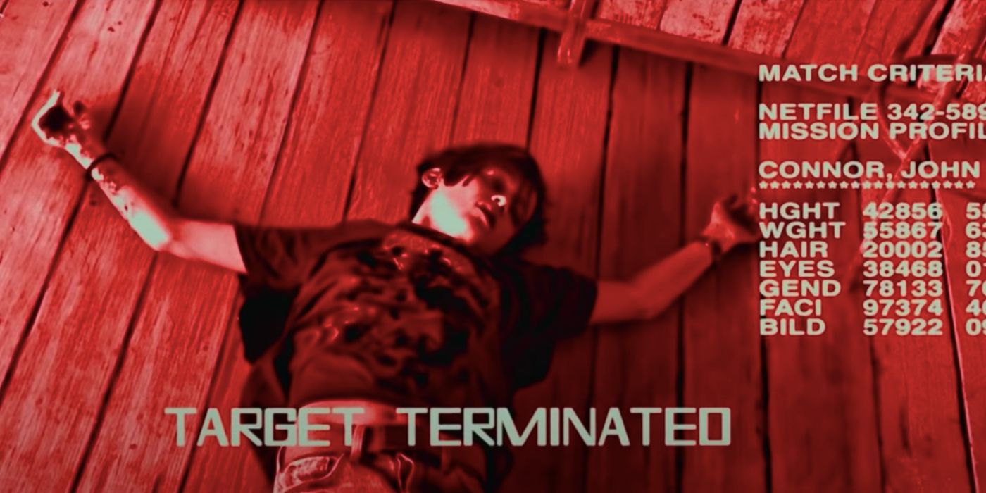 Screencap from Terminator: Dark Fate. POV shot of the T-800 looking down at the corpse of a young John Connor based on Edward Furlong's likeness. Image is filtered in red, with text at the bottom reading 