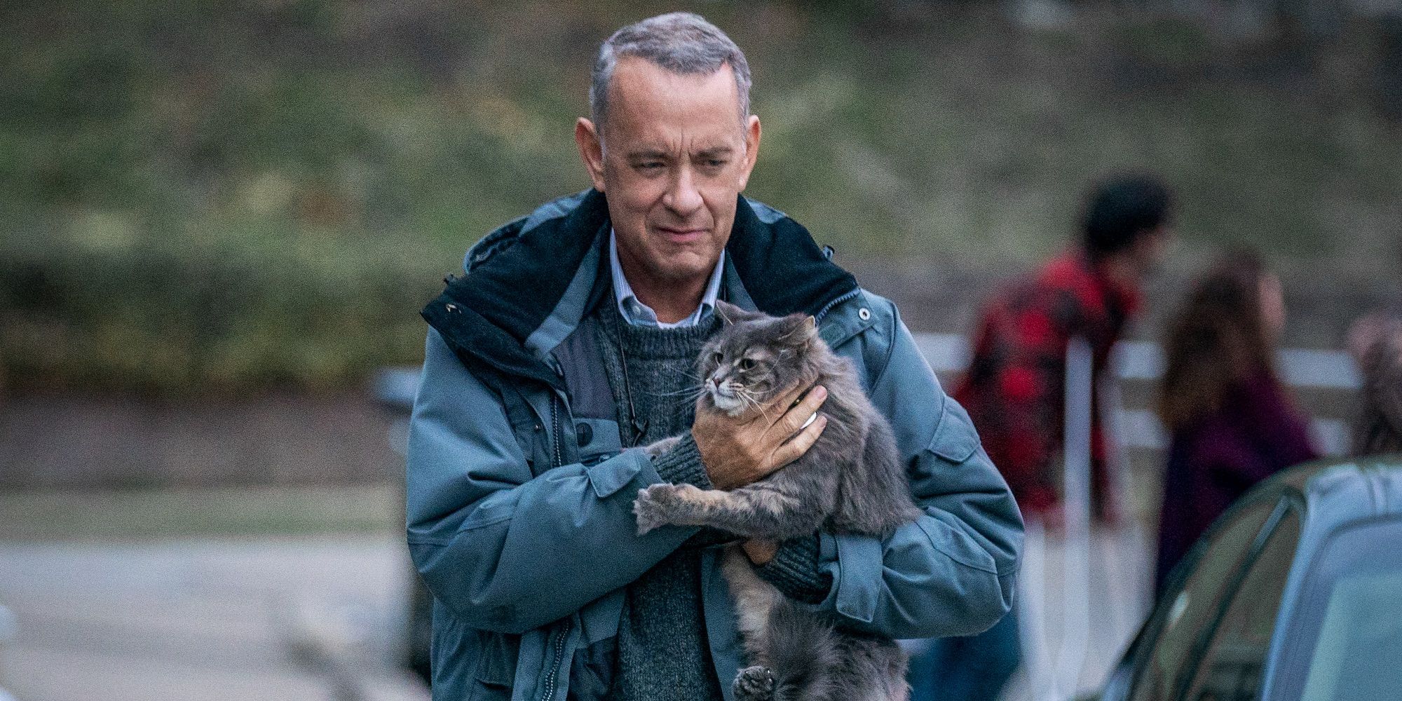 Tom Hanks smiling and holding a cat in A Man Called Otto