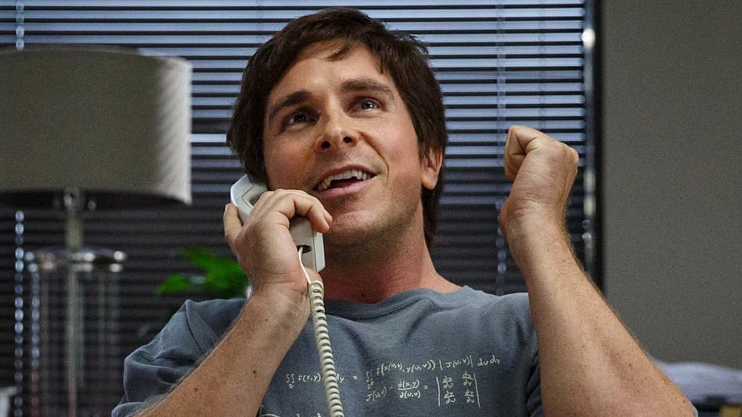 Christian Bale as Michael Burry on the phone looking excited in The Big Short