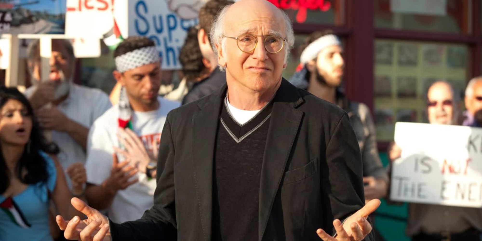 Larry David shrugging in front of a protest in Curb Your Enthusiasm.