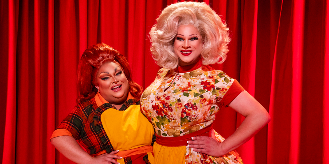 drag me to dinner 22 two cast members posing with smiles in front of red curtain