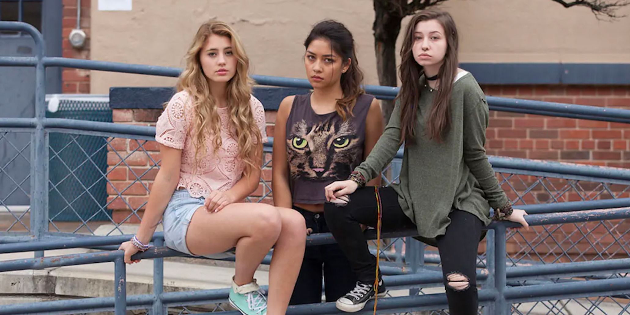 Hailey, Rowan, and Elisia on the fence outside school in T@gged
