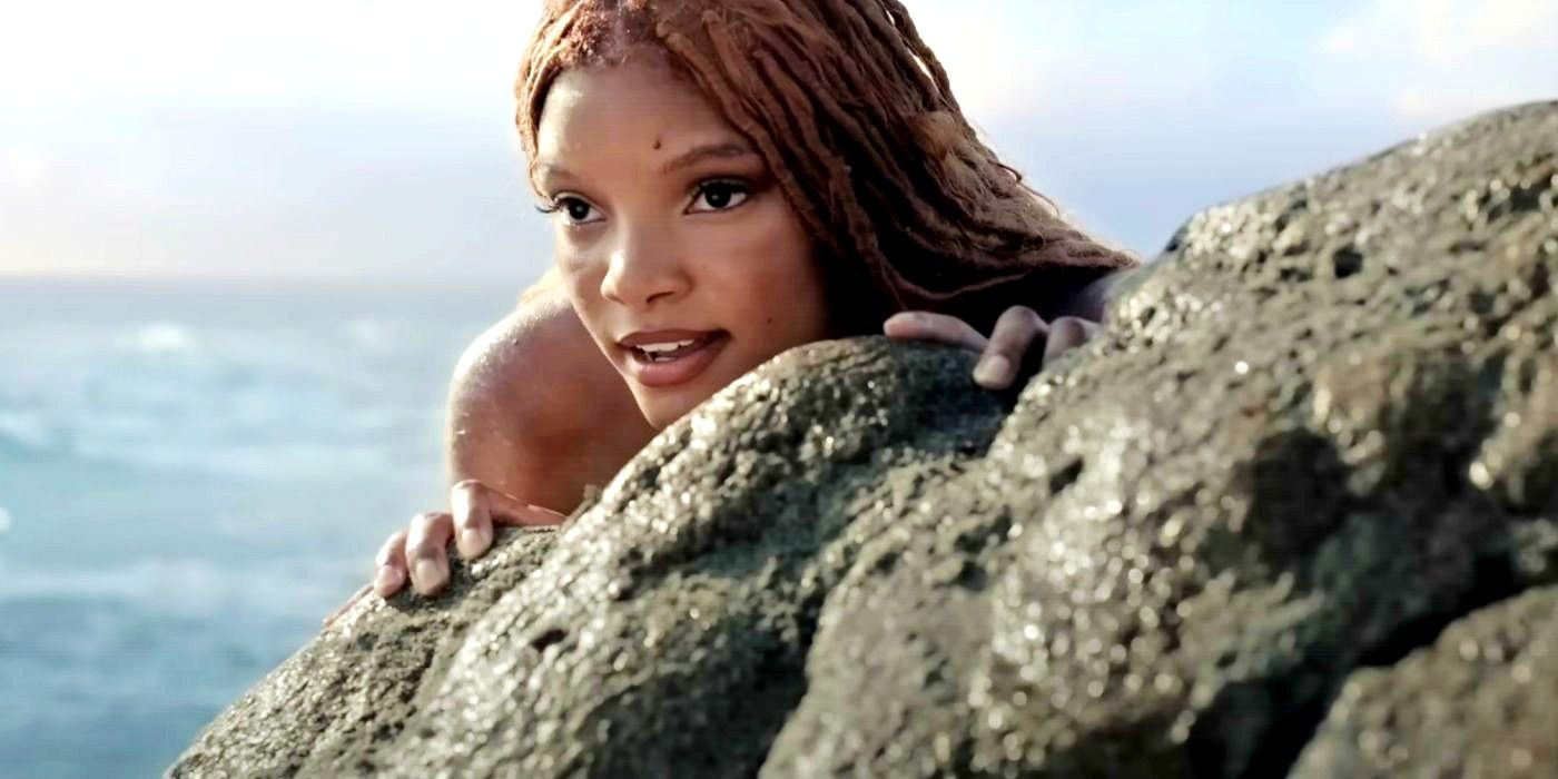 Halle Bailey as Ariel hiding behind a rock in The Little Mermaid