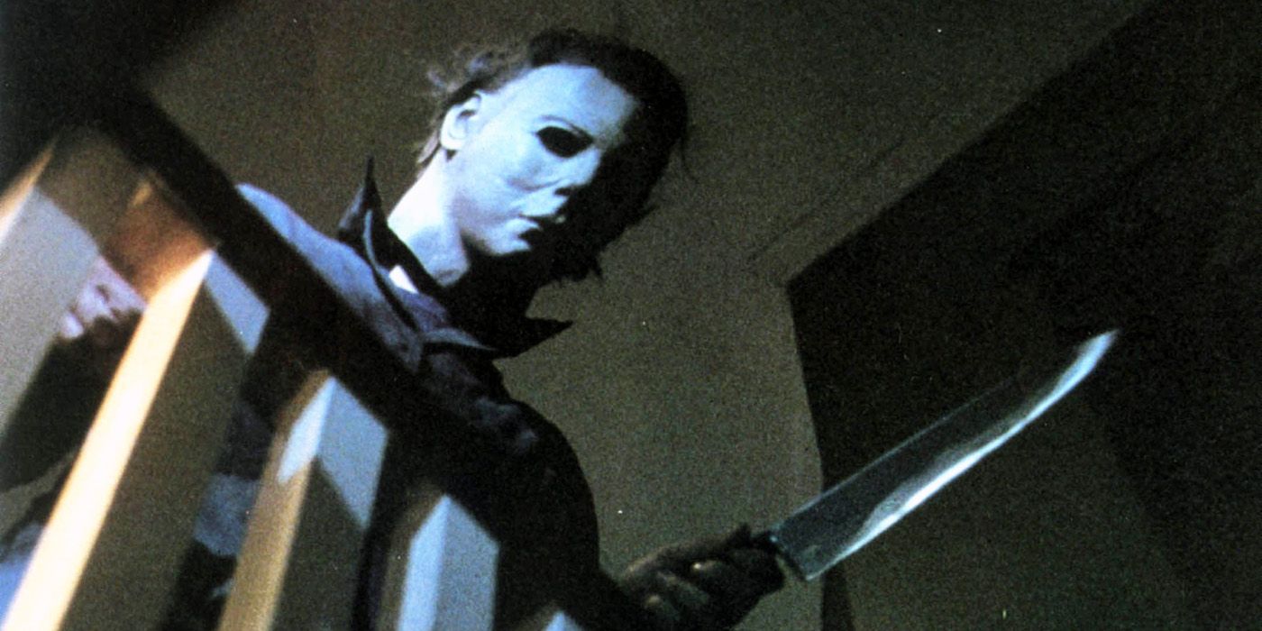 Nick Castle as Michael Myers looking over a balcony holding a knife in the original Halloween movie from 1978