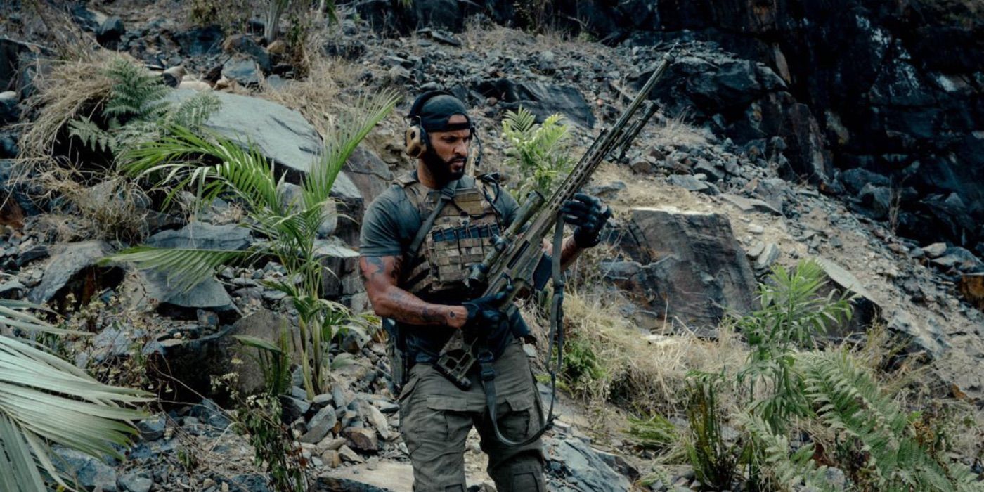 Ricky Whittle as Bishop stands on a hillside with a large gun in Land of Bad