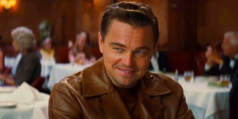 Rick Dalton (Leonardo DiCaprio) smiles while sitting at a restaurant in Once Upon a Time in Hollywood.