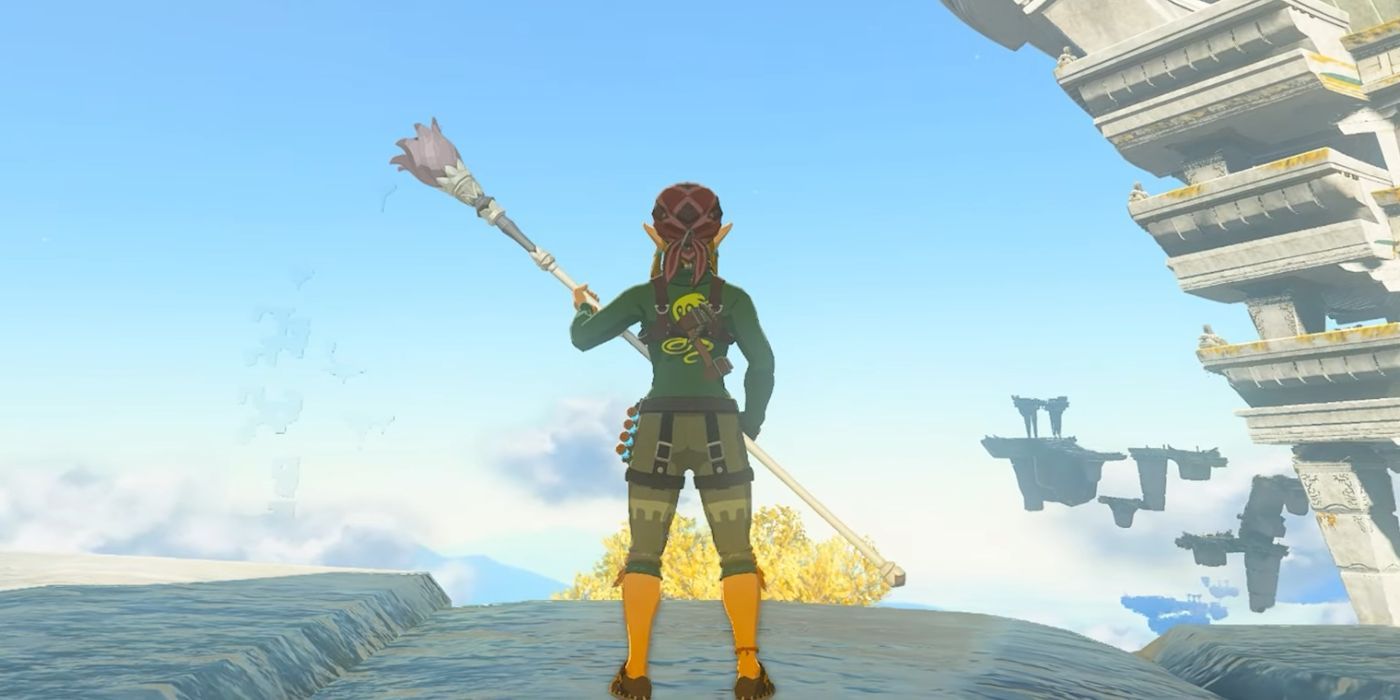 Link standing on a cliff near the Temple of Time, holding the Magic Staff in Zelda: Tears of the Kindgom.