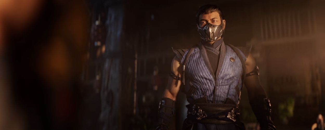 Mortal Kombat 1's Sub-Zero stands in a dark room while wearing his blue outfit.