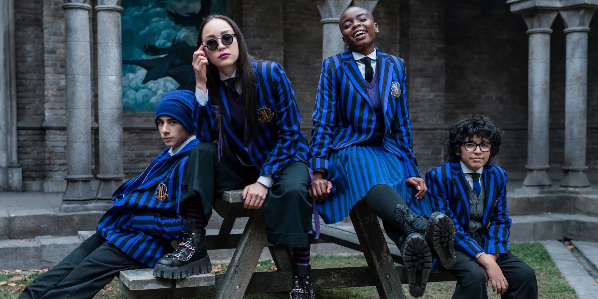 Wednesday, Yoko, Bianca, and the other Nevermore Academy students sit at a picnic table.