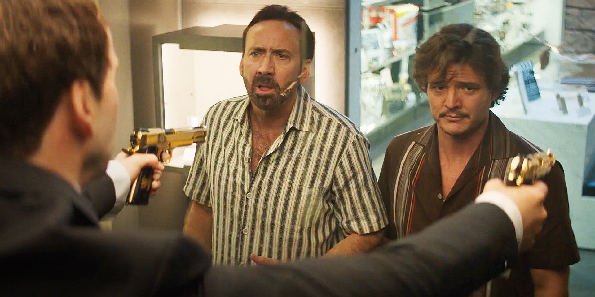 Nicolas Cage and Pedro Pascal looking at a Nicolas Cage statue in The Unbearable Weight of Massive Talent