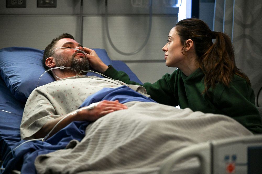 Ruzek in the hospital bed as a woman strokes his face
