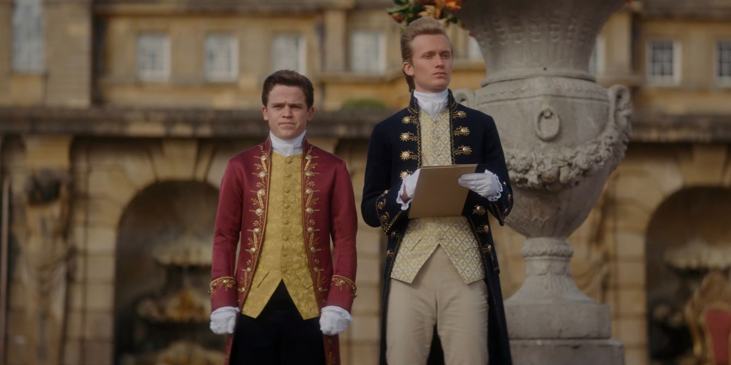 Brimsely and Reynolds stand next to one another and pretend not to talk in Queen Charlotte