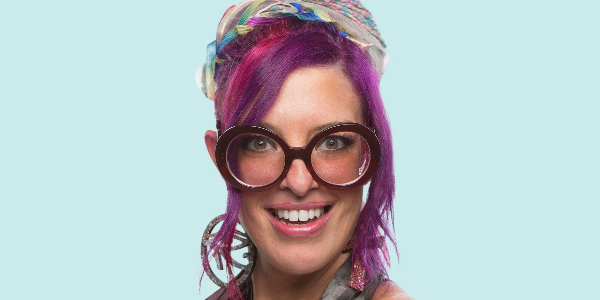 Big Brother Rockstar smiling in headscarf and glasses purple hair