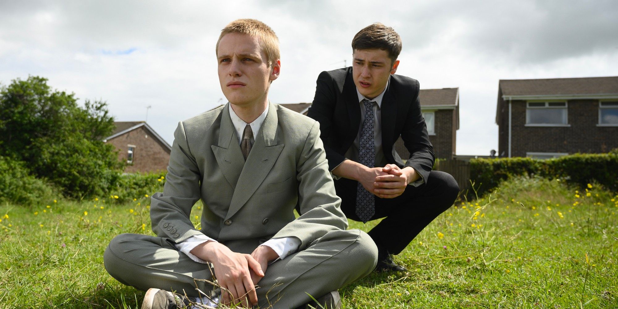 Two men sit in a field in Somewhere Boy