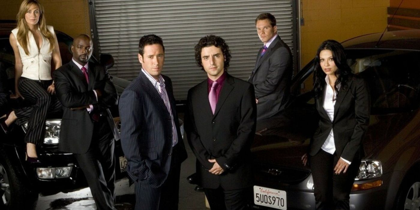 The cast of Numb3rs in a promotional image with them standing in front of or leaning on cars