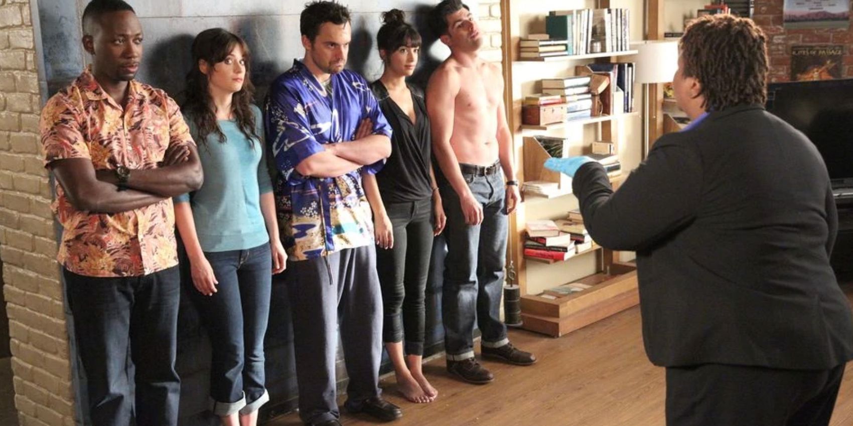 The roommates line up against the wall while a police officer talks to them in the New Girl episode Background Check